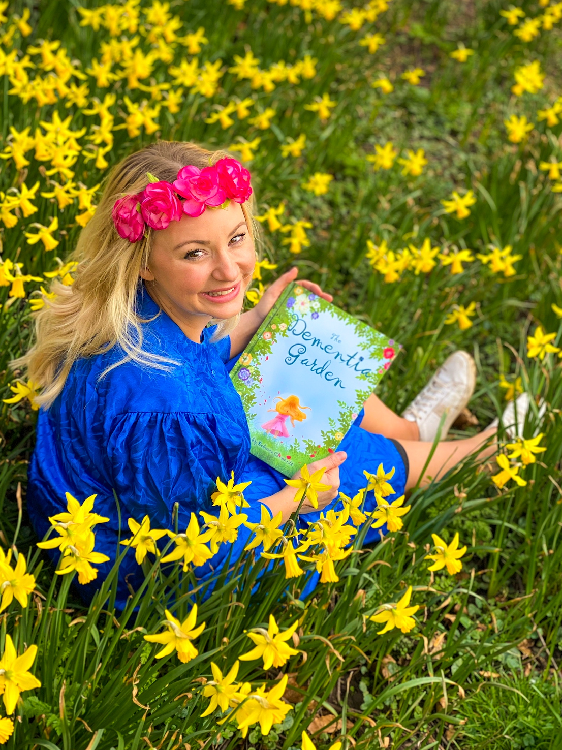 Rebecca holding The Dementia Garden among daffodils